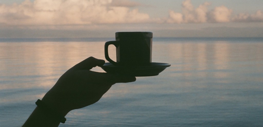 coffee cup in hand over water
