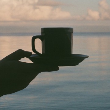 coffee cup in hand over water