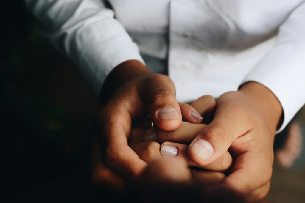 people holding hands, one wearing white buttondown shirt