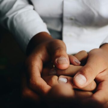 people holding hands, one wearing white buttondown shirt